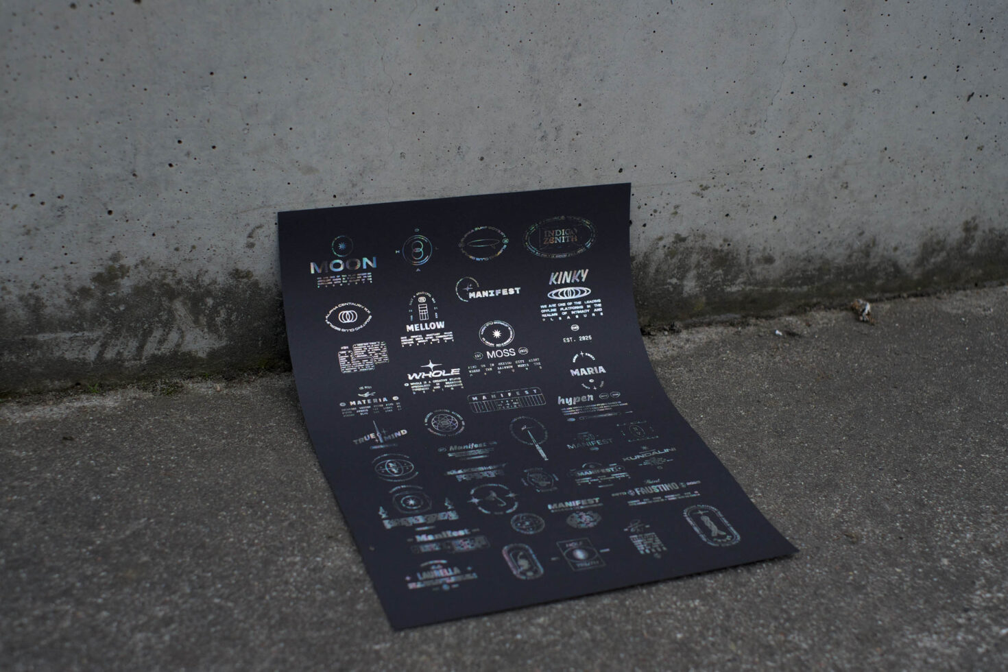 Dark navy poster with white logo designs scattered across cracked concrete ground