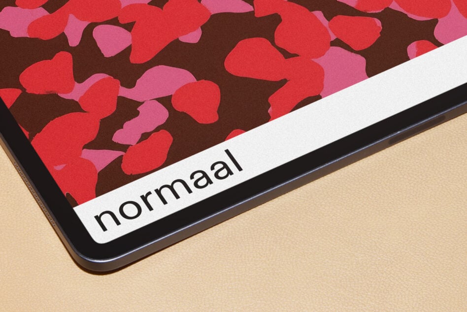 Tablet showing red floral pattern with normaal branding label on beige surface