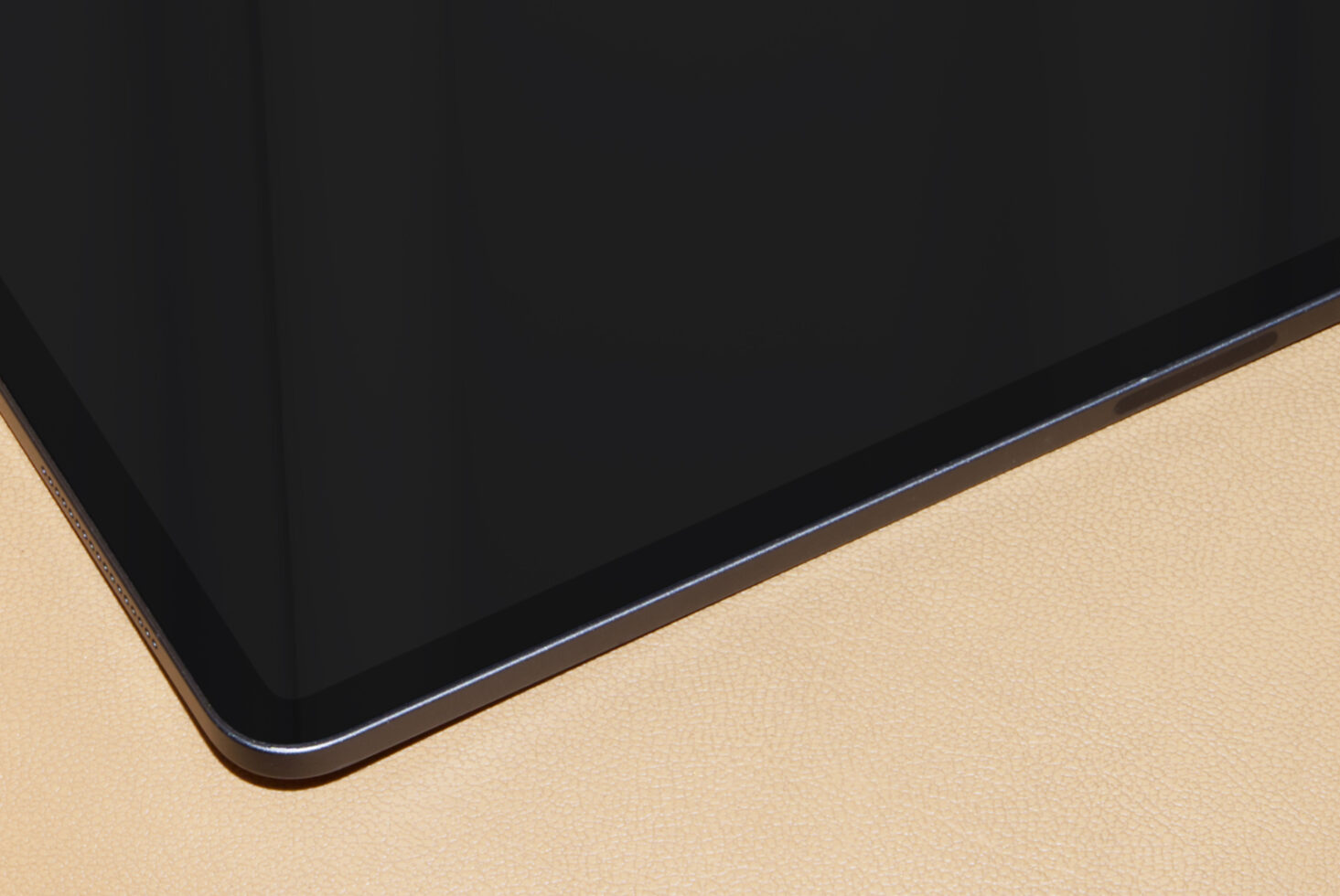 Tablet device with black screen on beige textured surface