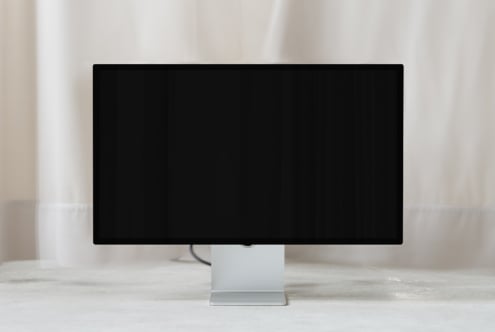 Desktop monitor mockup with blank black screen on white stand