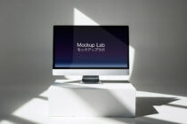 Desktop monitor on white cube showing Mockup Lab screen with Japanese text