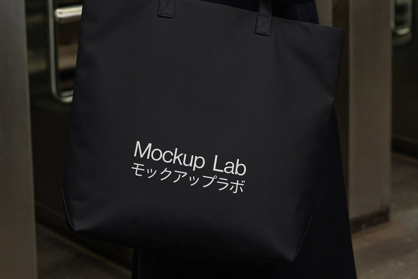 Black tote bag with white text mockup held by handles