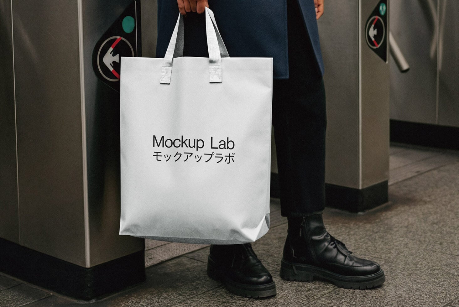 White tote bag with Mockup Lab text held by person in subway station