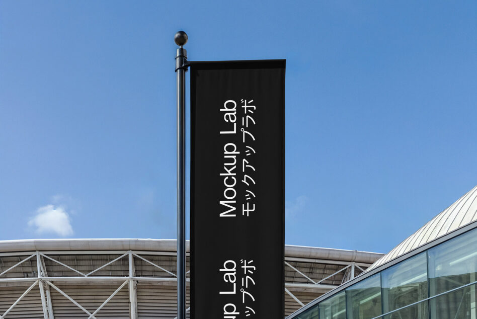 Dark vertical banner on metal pole against clear blue sky outdoor setting