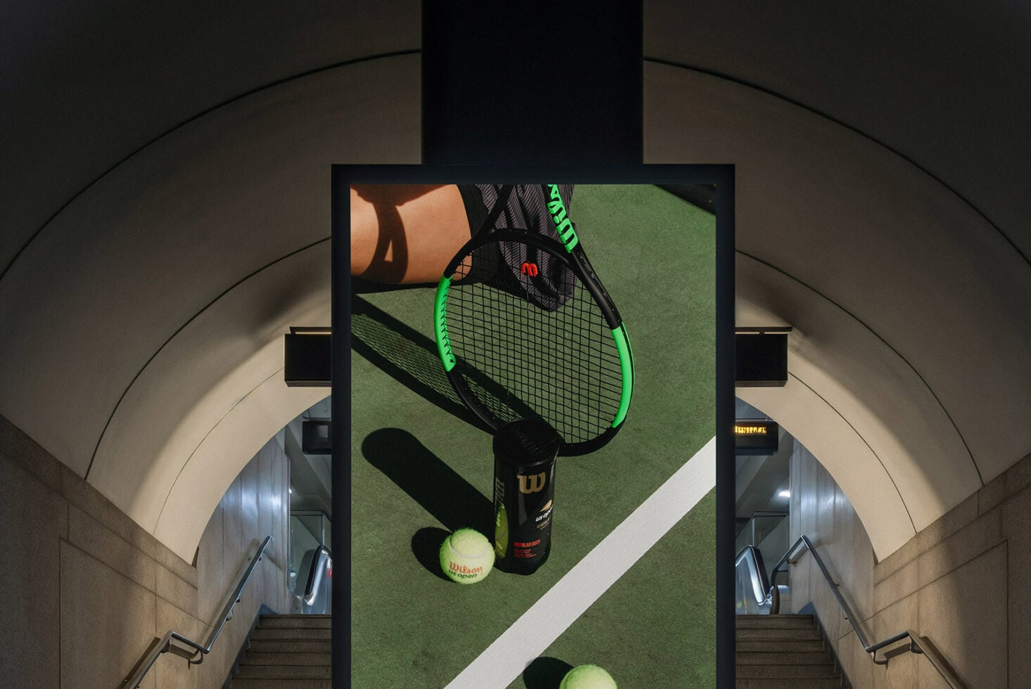 Digital display in stairwell showing overhead tennis racket, balls, sports gear setup