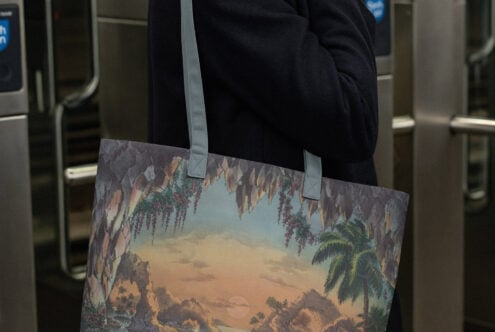 Person wearing printed tote with vintage tropical cave landscape illustration