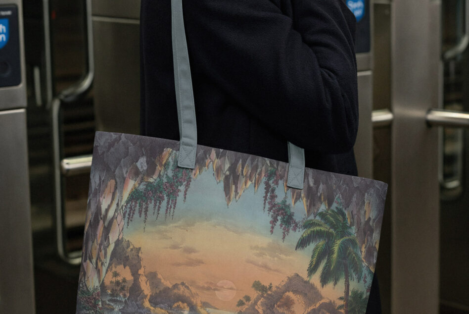 Person wearing printed tote with vintage tropical cave landscape illustration