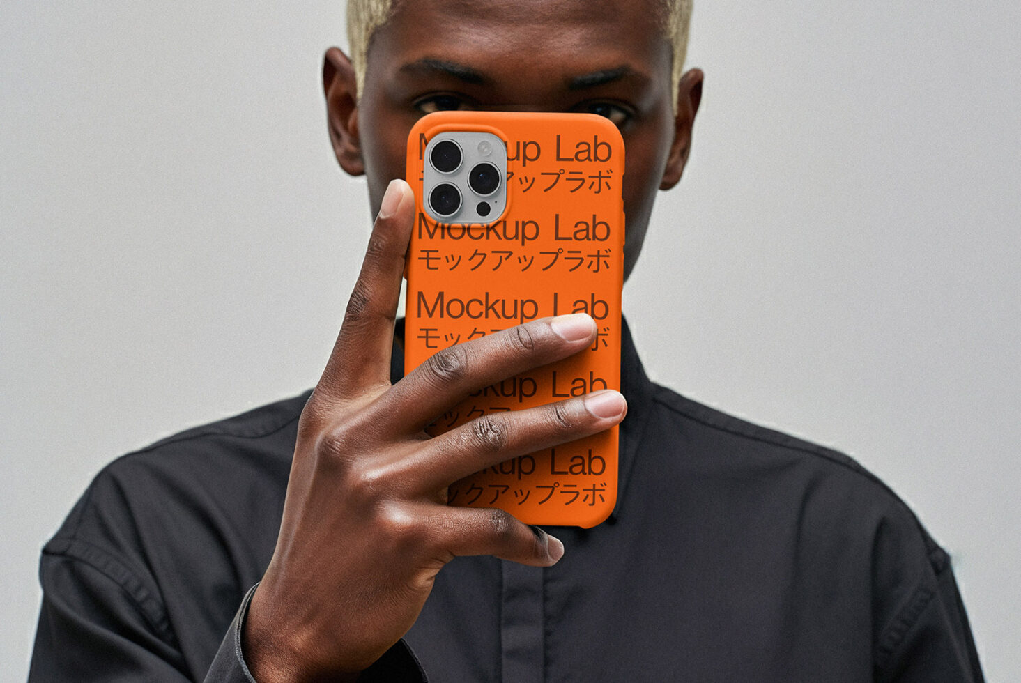 iPhone 12 Pro case mockup in vibrant orange held up covering person's face in black shirt