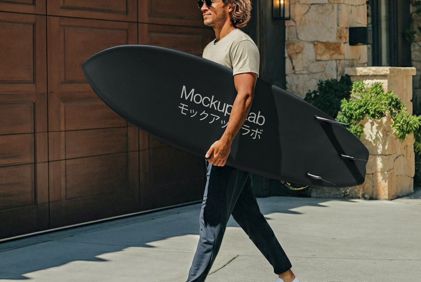 Man carrying black surfboard mockup in sunny coastal setting
