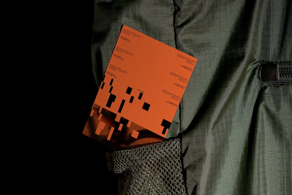Bright orange clothing label mockup with black geometric shapes, shot flat lay on textured fabric