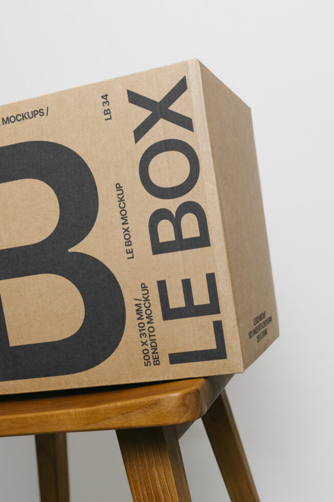 Kraft cardboard box mockup with black X symbol, sitting on wooden stool