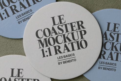 Cream circular coaster mockup displayed among blue versions on cloth surface