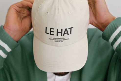 Cream cap front view with LE HAT branding, hands in green hoodie