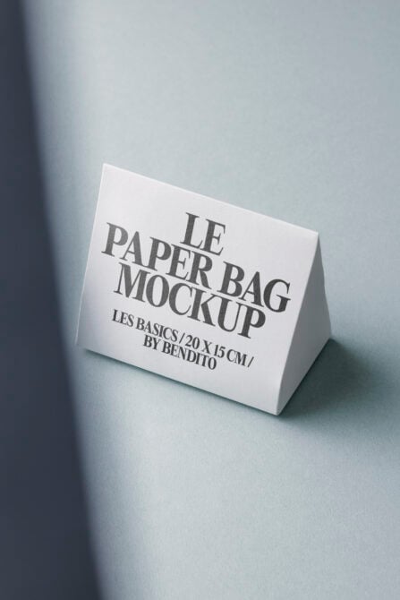 White folded paper bag mockup on cool grey surface with dramatic lighting