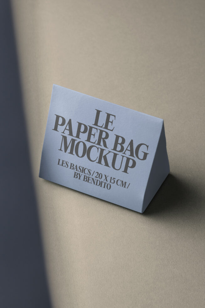 Light blue paper bag mockup angled on warm beige with soft shadow