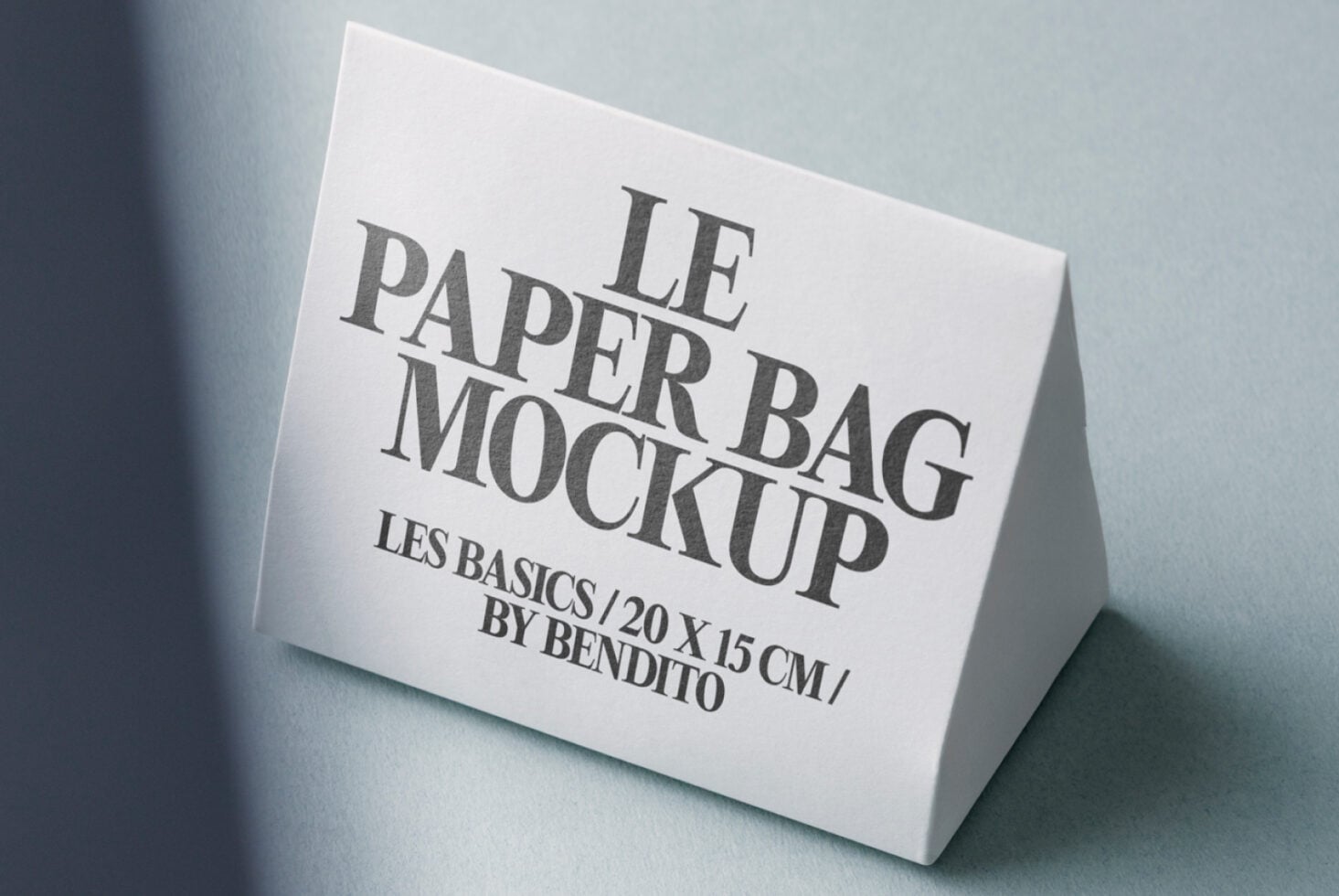 White paper bag mockup positioned on soft blue-grey surface with shadows