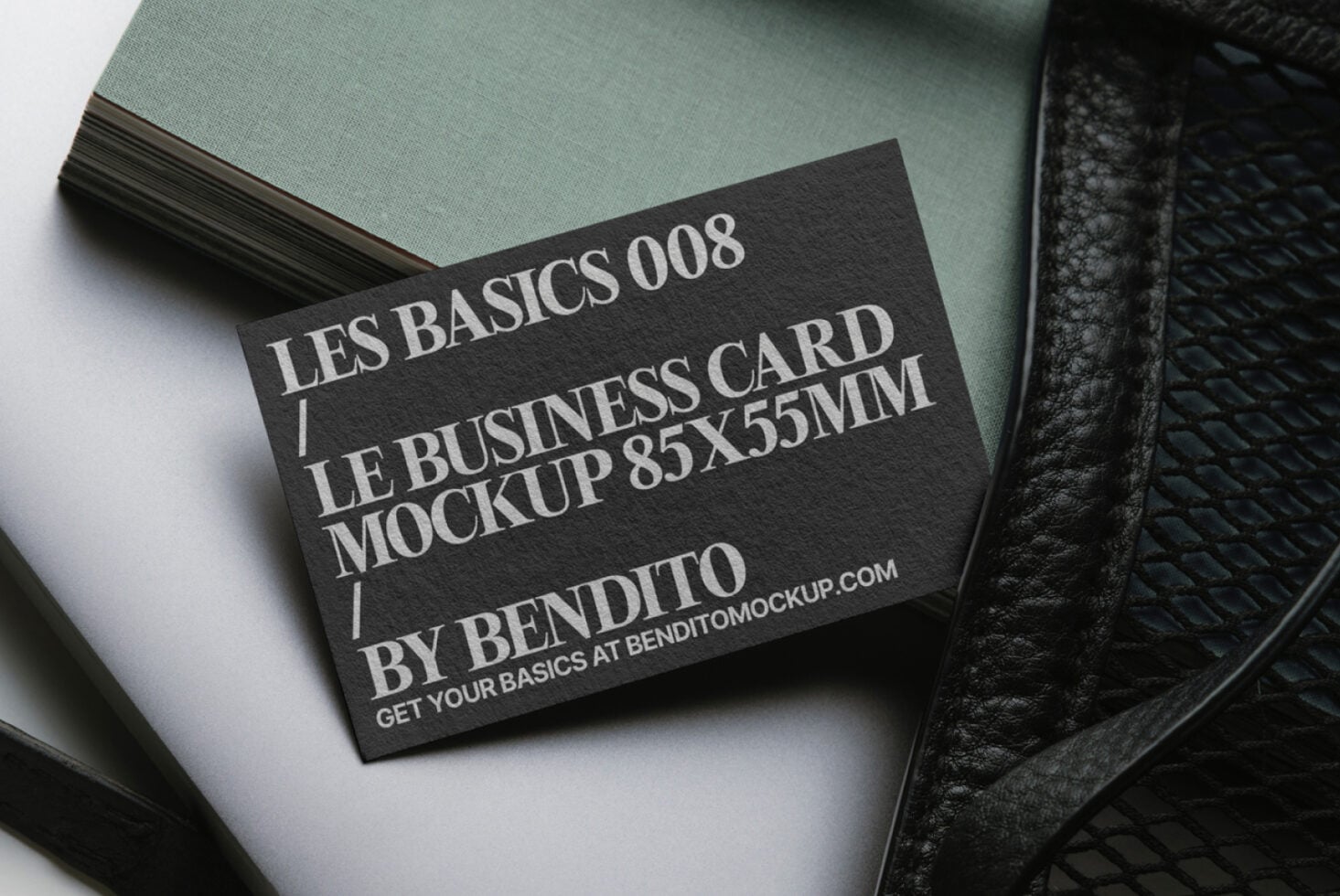 Dark card mockup on sage green paper stack with black leather accessory styling