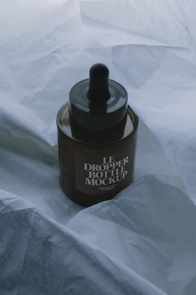 Dark amber dropper bottle mockup on white fabric with natural lighting