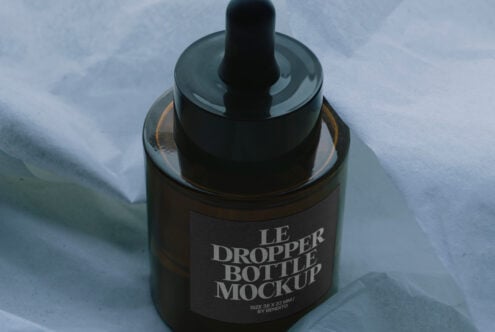 Dark amber glass dropper bottle mockup shot overhead with fabric