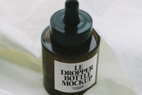 Dark amber dropper bottle with label mockup on soft fabric surface