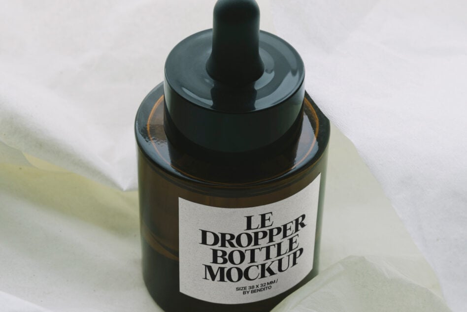 Dark amber dropper bottle with label mockup on soft fabric surface