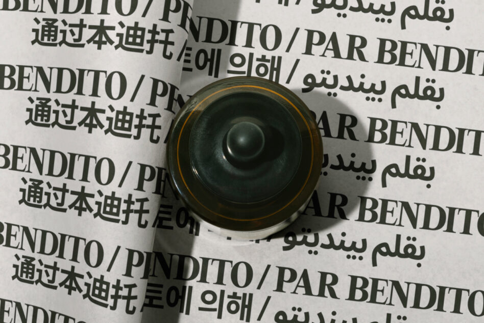Overhead view of rolled paper mockup with multilingual text, gold-rimmed black speaker centered