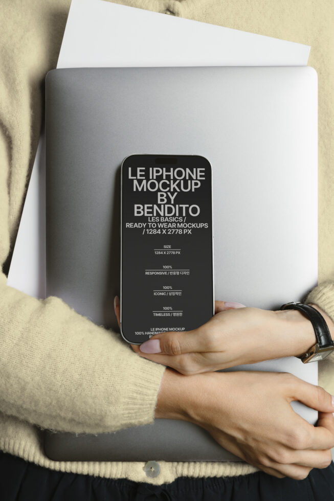 Person holding silver laptop with black iPhone mockup overlay on screen