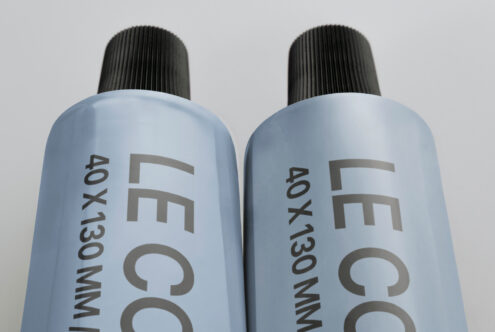 Twin light blue spray bottles with black textured caps, angled view