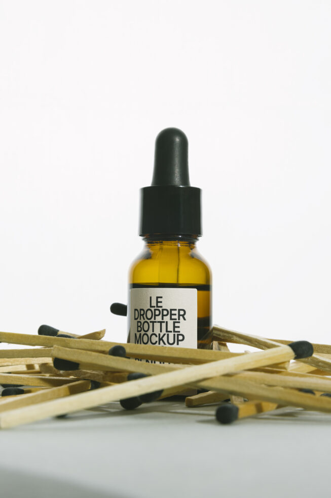 Golden yellow oil dropper bottle with black cap nestled in wooden matches