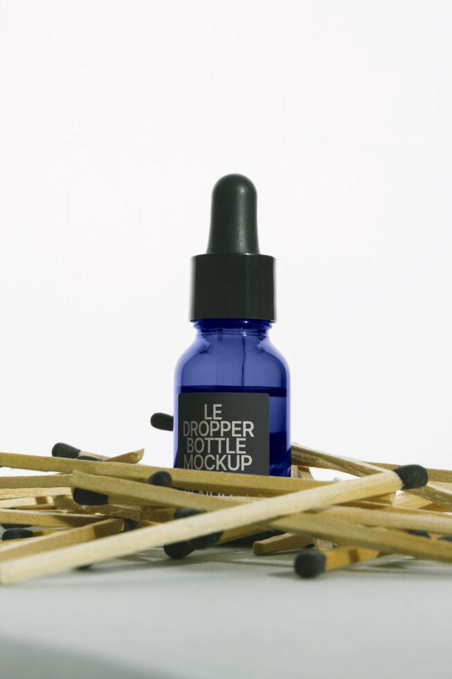 Cobalt glass dropper bottle with black cap surrounded by wooden matches