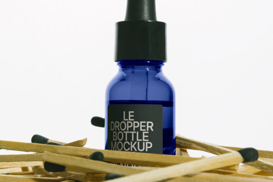 Cobalt blue dropper bottle with black cap surrounded by wooden matchsticks