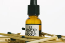 Golden amber dropper bottle with black cap on scattered wooden matchsticks