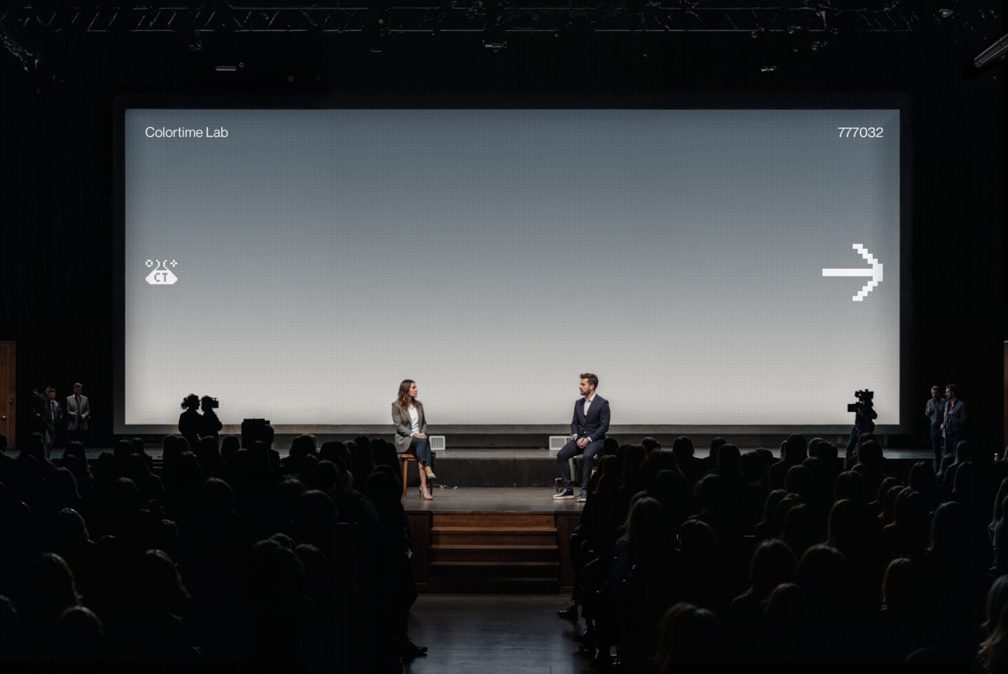 Auditorium projection screen with blue-gray gradient displaying white pixel arrow