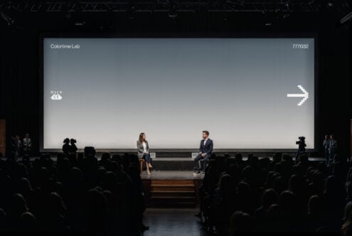Auditorium projection screen with blue-gray gradient displaying white pixel arrow