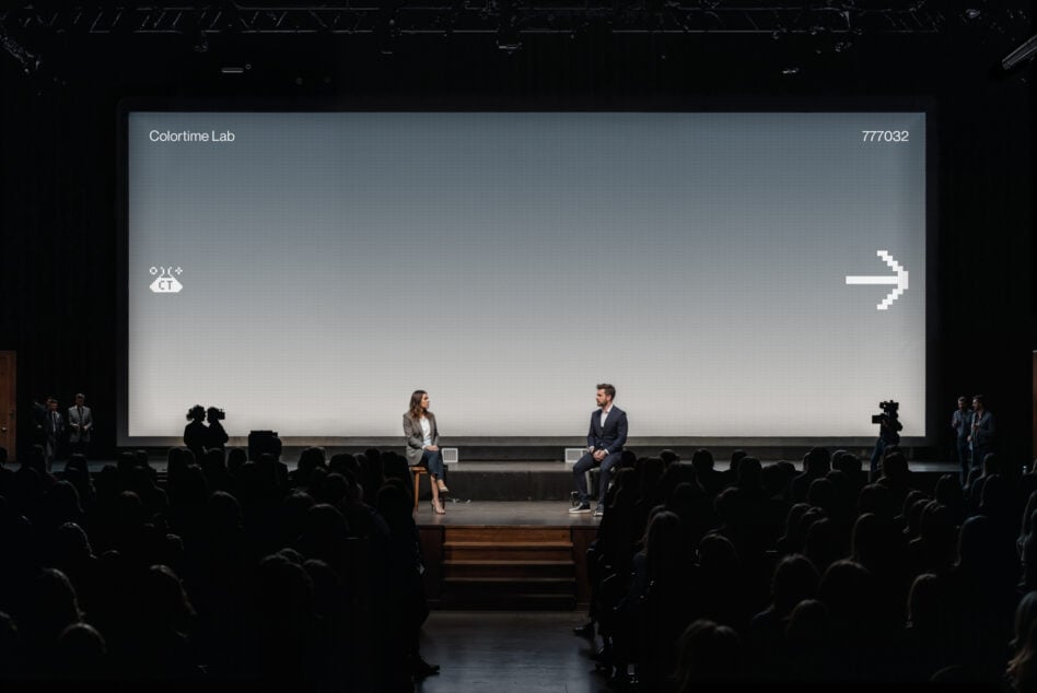 Auditorium projection screen with blue-gray gradient displaying white pixel arrow