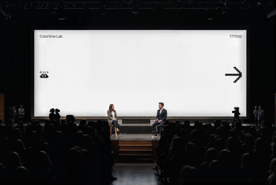 Large auditorium screen with bright white background showing black pixel arrow symbol