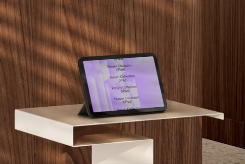 iPad in black case on cream shelf against wood wall, purple gradient on screen