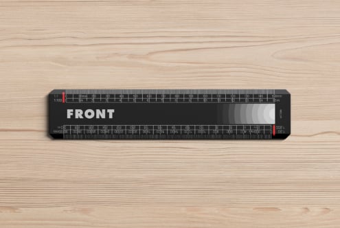 Black scale ruler with white markings on light wooden surface flat lay