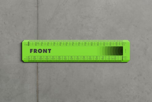Neon green scale ruler with detailed markings on concrete floor backdrop
