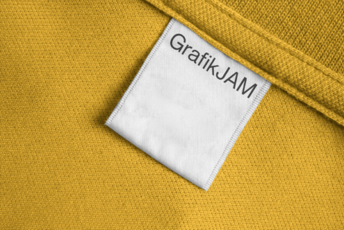 Mustard yellow garment with white woven label showing Grafik JAM brand text