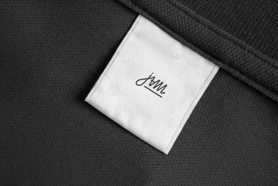 Black knit fabric with white care label displaying minimalist script signature