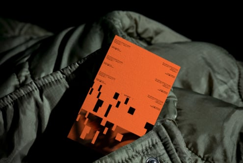 Orange clothing label mockup draped on green quilted fabric with dramatic shadows