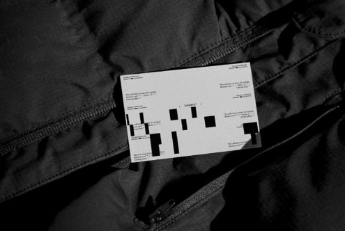 White garment label mockup placed on dark textile material with zippers