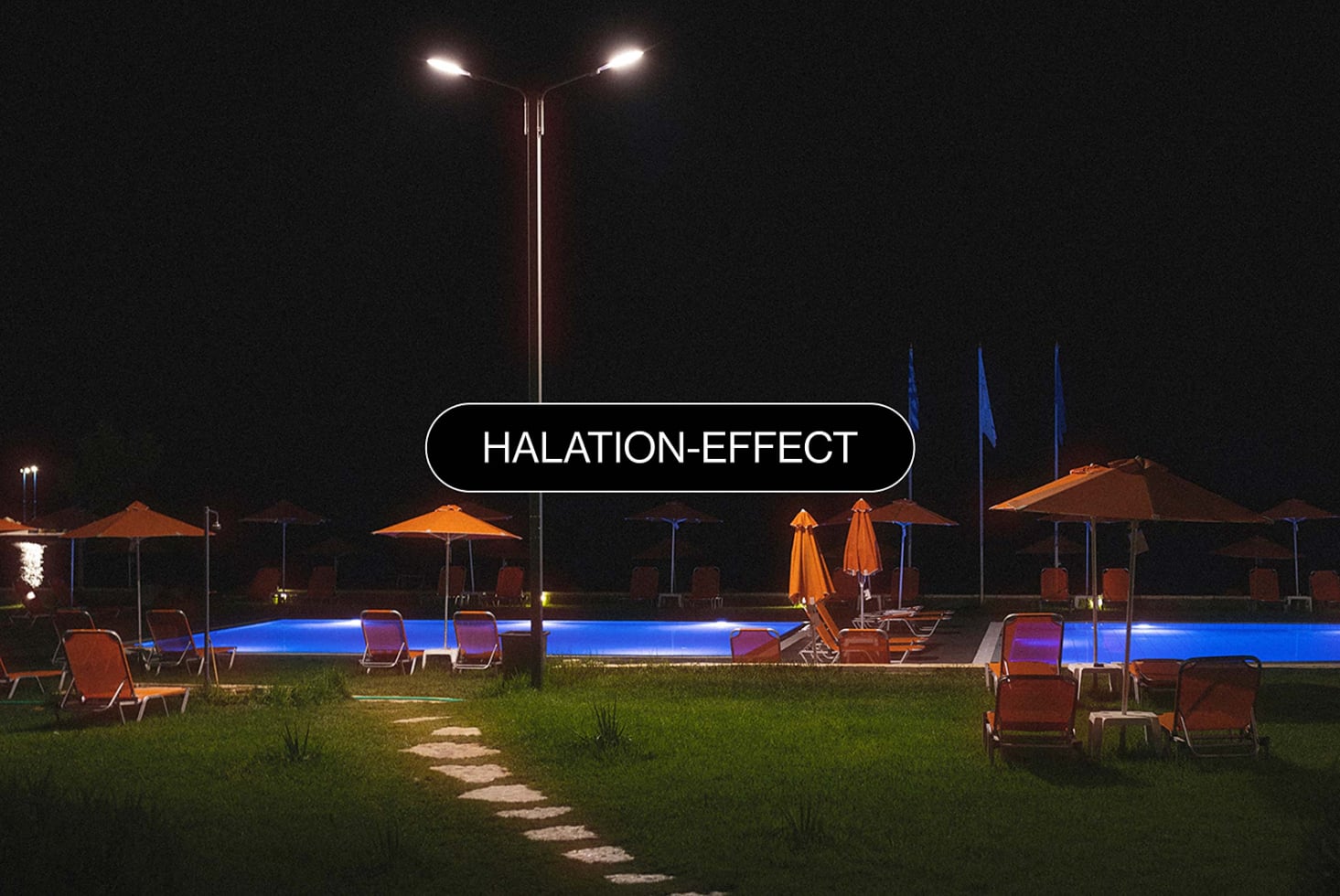 Illuminated poolside scene at night showing warm halation effect on landscape