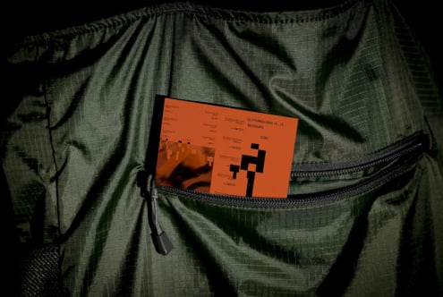 Orange clothing label mockup card inside open green jacket pocket