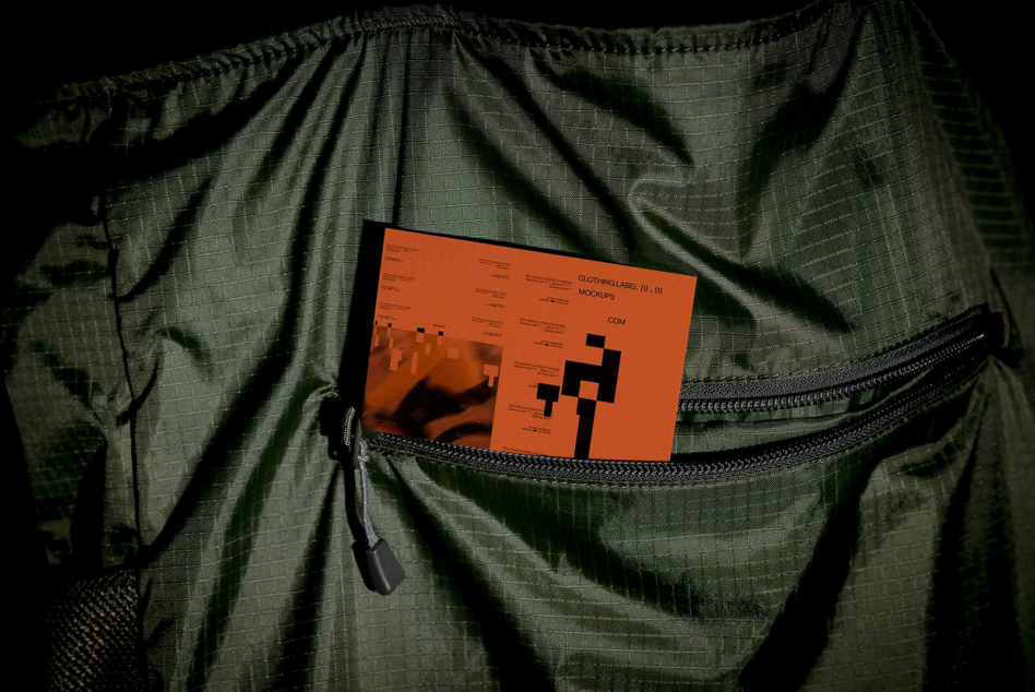 Orange clothing label mockup card inside open green jacket pocket