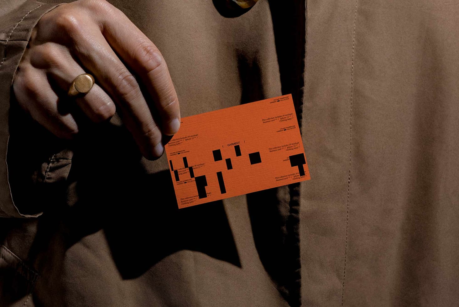 Orange business card with black geometric layout held in hand wearing gold ring