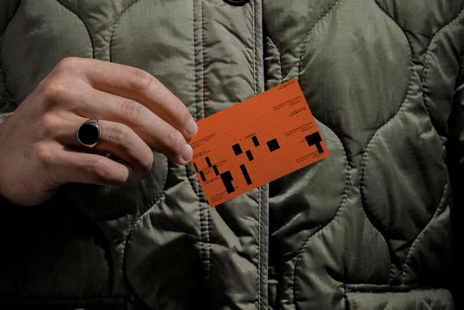 Person in quilted jacket holding orange label mockup with pixelated design