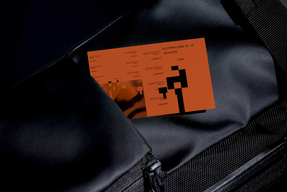 Orange clothing label mockup folded on dark navy fabric with geometric cutout