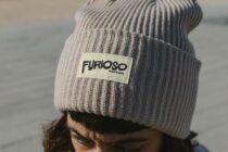 Gray knit beanie with cream woven label displaying Furioso text